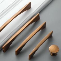 an assortment of wooden handles and knobs on a gray surface next to a white curtain