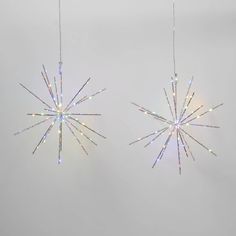 two christmas lights hanging from strings in the shape of snowflakes on a white background