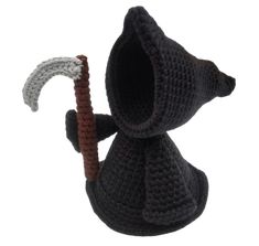 a crocheted stuffed animal holding a stick and wearing a knitted black hat