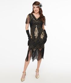 This stunning 1920s flapper dress features a dazzling array of gold beads and sequins throughout a dramatic 1920s silhouette. This dress is crafted with a black mesh overlay with a v-neck and adorable cap sleeves. The tulip hemline sways with long black fringe.Available in sizes S-3X while supplies last.This is a Special Order item, please allow a 2-3 day handling time. Fitted Flapper Dress For Festive Occasions, Festive Fitted Flapper Dress, Festive Fitted Flapper Dress For Costume Party, Fitted Flapper Dress For Festive Costume Party, Gold Fitted Flapper Dress For Costume Party, Gold Gatsby Flapper Dress For Summer, Gold Flapper Dress For Summer, Black Beaded Fringe Flapper Dress, Fitted Flapper Dress With Sequins And V-neck