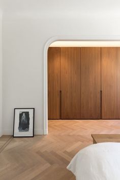 an empty bedroom with wooden closets and pictures on the floor in front of it