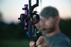 a man holding up a bow with his hand and looking through the scope at it