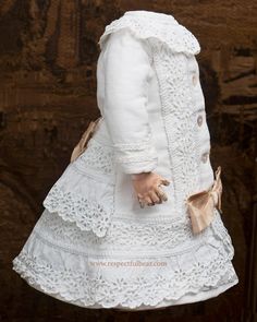 a doll is wearing a white dress and hat