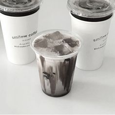 three different types of drinks in plastic cups on a white surface with the lids down