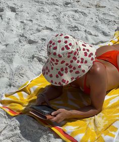 a woman laying on top of a yellow and white towel next to a cell phone