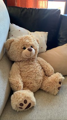 a brown teddy bear sitting on top of a couch