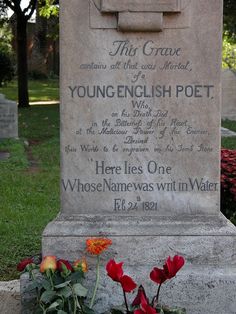 the grave of young english poet is surrounded by red flowers and greenery in front of it