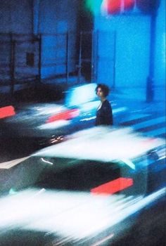 a blurry photo of cars driving down a street at night with a man standing in the middle