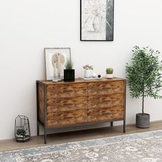 a wooden dresser sitting on top of a hard wood floor next to a potted plant