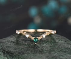 an emerald and diamond ring sitting on top of a rock