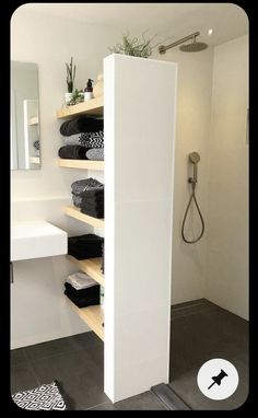 a white bathroom with shelves and towels on the wall