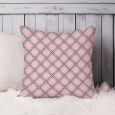 a pink plaid pillow sitting on top of a white furnishing next to a wooden headboard