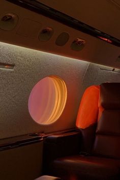 the inside of an airplane with leather seats and round lights on the wall above it