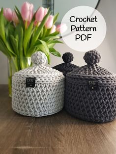 two crochet baskets sitting on top of a wooden table next to a vase with flowers