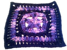 a crocheted square with a purple and black design on the center is shown