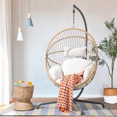 a hanging chair in the corner of a room with pillows on it and a potted plant next to it