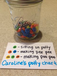 a jar filled with gummy bears sitting on top of a table next to a sign