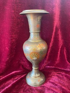 a silver vase sitting on top of a red cloth