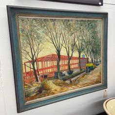 a painting hanging on the wall next to a table with a plate and bowl in front of it