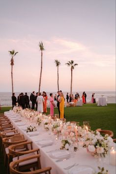 a long table is set up with candles and flowers for an outdoor dinner by the beach