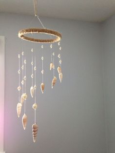 a mobile with seashells hanging from it's sides in a room next to a window