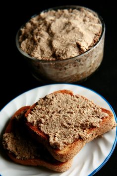 two pieces of bread sitting on top of a white plate next to a bowl of food