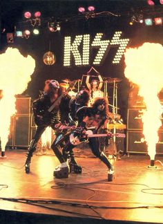 the band kiss performing on stage with flames