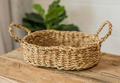 a woven basket sitting on top of a wooden table next to a potted plant