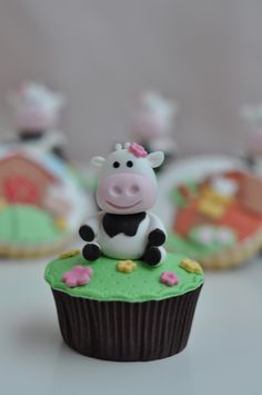 a cupcake with a cow sitting on top of it next to other cupcakes