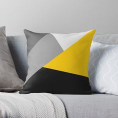 a grey, yellow and black pillow sitting on top of a couch