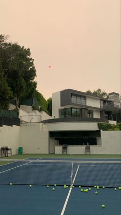 tennis balls are on the ground in front of a large building with two stories and an upper level balcony