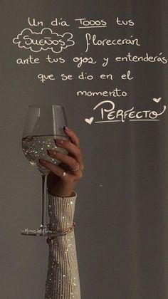 a woman holding a wine glass in front of a chalkboard with writing on it