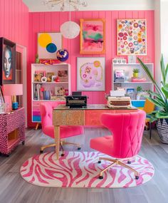 a room with pink walls and zebra print rugs on the floor, two chairs in front of a desk