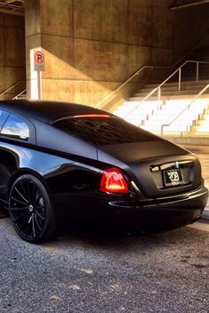 a black sports car parked in front of a parking garage with stairs leading up to it