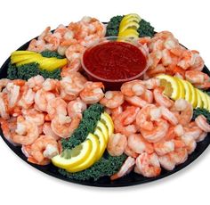 a plate with shrimp, broccoli, lemons and ketchup on it