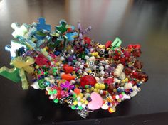 a bunch of different colored beads on top of a black table next to a cell phone