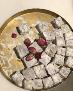 a metal bowl filled with sugar cubes and flowers on top of a white table