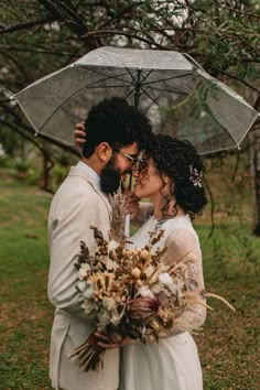 a bride and groom standing under an umbrella