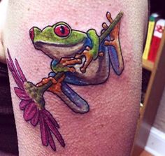 a frog with a dragonfly on its back tattooing it's legs and leg