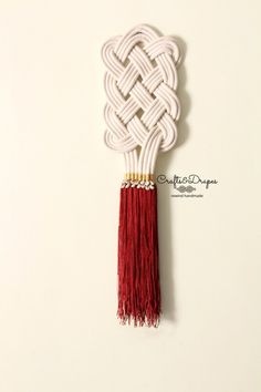 a white and red piece of art with tassels