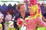 two people dressed in colorful clothing standing next to each other with flowers on their heads