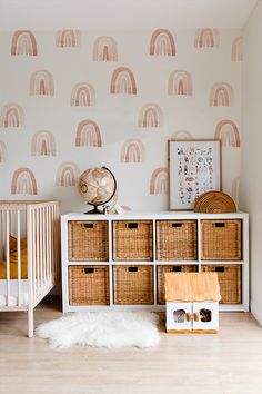 a baby's room with pink and white wallpaper, wicker baskets, and a crib