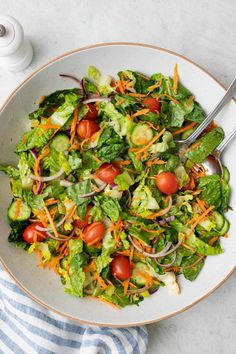 a salad with lettuce, carrots and cucumbers in a bowl