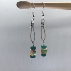 Recycled Guitar String earrings Multi color square bead and green beads I make guitar string jewelry from used strings donated from local Charlotte musicians and traveling musicians that play at our home.  Some beads are donated by friends, others I have found in antique stores.  When artist play in our home, the funds from any jewelry that is sold that night are donated to the artist that is playing.  We love music and this is our way of giving back to the music industry with fun art. Wire Guitar Jewelry, Guitar Chip Necklace, Flat Bracelet, Guitar Pendant, String Earrings, Guitar String Jewelry, String Jewelry, Makeup Purse, Coin Card