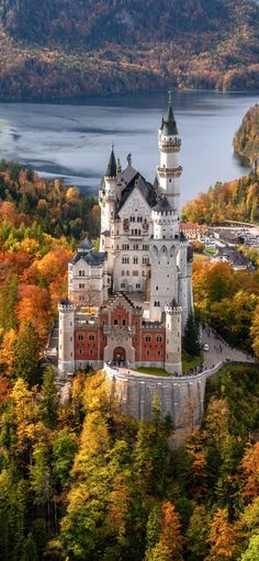 an aerial view of a castle in the middle of trees with fall foliage surrounding it