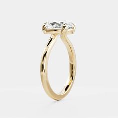 a yellow gold engagement ring with an oval cut diamond in the center, on a white background