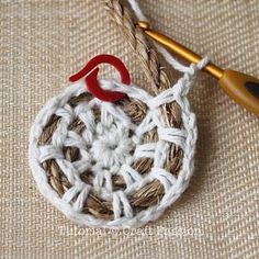 a crocheted piece with a red hook on it sitting next to a knitting needle