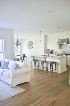 a living room filled with furniture next to a kitchen and dining room table on top of a hard wood floor