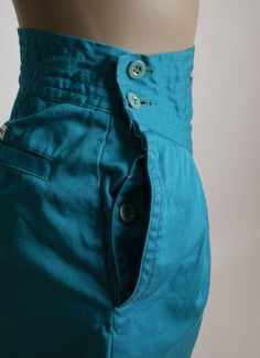 "FREE DOMESTIC SHIPPING! <3 ♥ Super fun pair of 1990s turquoise blue high waist shorts! ♥ They button close on the side! Fun buckle on the front waist, which serves no purpose other than looking adorable! ;) ♥ Very high waisted! Wide legs that have a flare to them (I pulled them into a point on the back shot) ♥ Front pleats. Has side pockets on both sides, as well as back pockets. ♥ Great vibrant turquoise aqua blue color! ♥ In great condition! There's some color bleed onto the tags and pocke Blue Cotton Pants With Built-in Shorts, Fitted Blue Bottoms With Hip Pockets, Retro Blue Bottoms With Pockets, Blue Straight-leg Bottoms With Buttons, Blue Straight Leg Bottoms With Buttons, High Rise Blue Pants With Buttons, Retro Cotton Bottoms With Buttons, Blue Cotton Shorts With Buttons, Vintage Cotton Short Pants