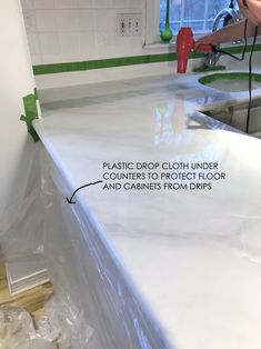 a kitchen counter being painted white with the words plastic drop cloth under counters to protect floor and cabinets from molds